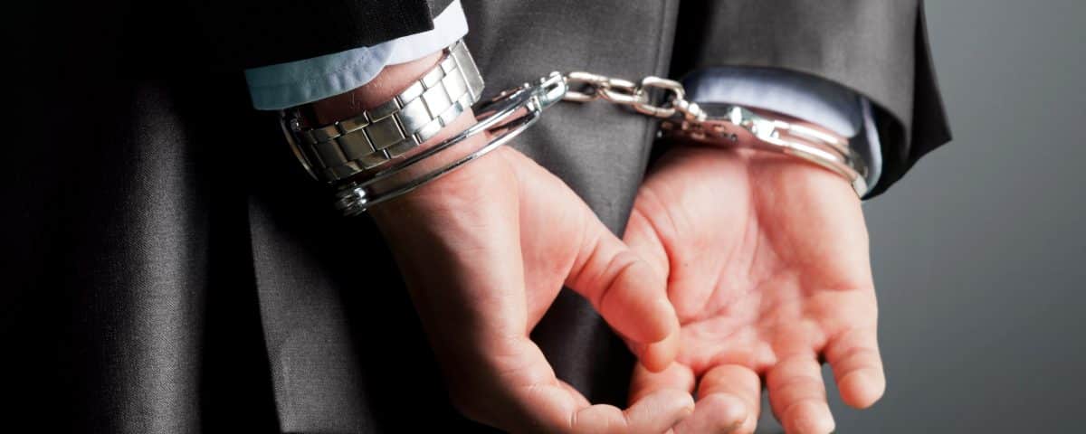 suited man's hands in handcuffs