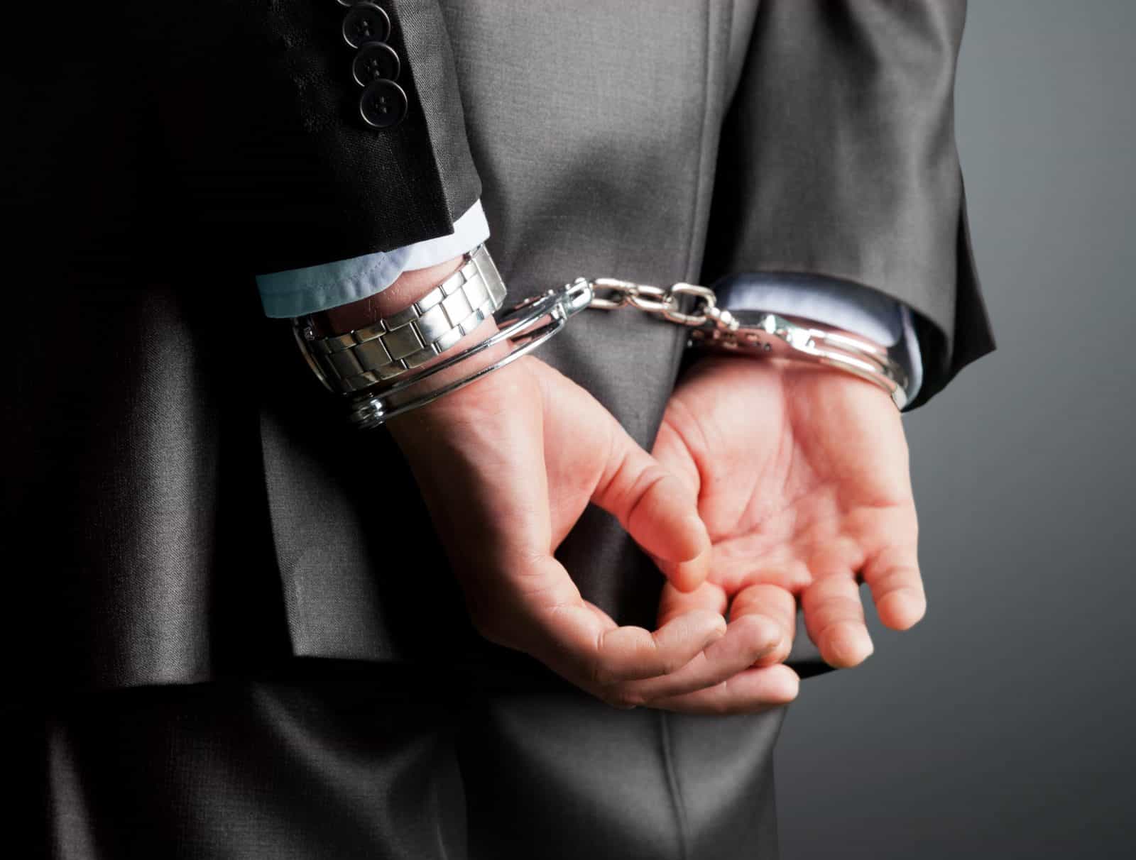 suited man's hands in handcuffs